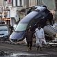 A couple walks past upturned vehicles sitting on a wall in the city of Miyako in Iwate prefecture on March 12, 2011 a day after a massive 8.9 magnitude quake and tsunami hit the region. An explosion at a Japanese nuclear plant triggered fears of a meltdown on March 12, after the massive earthquake and tsunami left more than 1,000 dead and at least 10,000 unaccounted for.     JAPAN OUT   RESTRICTED TO EDITORIAL USE     AFP PHOTO /YOMIURI SHIMBUN (Photo credit should read YOMIURI SHIMBUN/AFP/Getty Images)